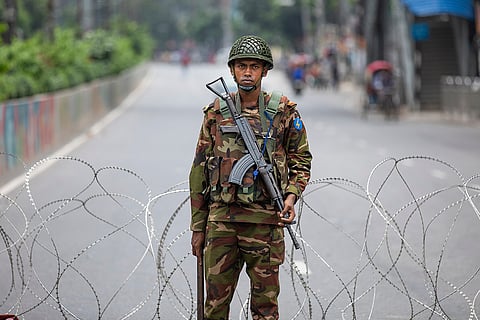 A soldier stands guard behind barbed wires